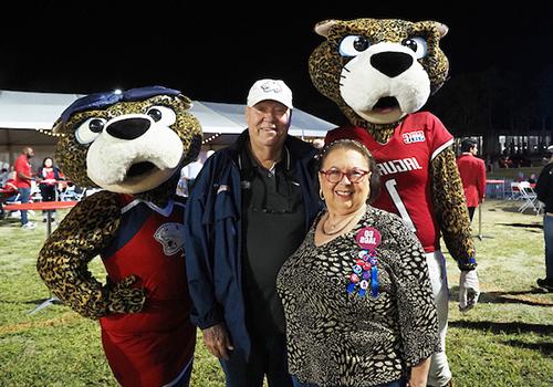 Two alumni members standing with Southpaw and Ms. Pawla.